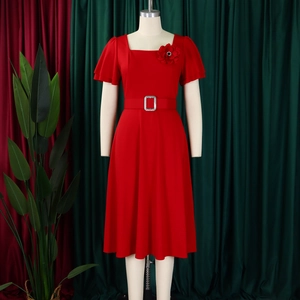 Detail of red square neck dress with bubble sleeves and matching belt with floral pin