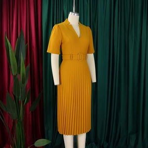 Détail d'une robe plissée col en V jaune gingembre avec ceinture et manches courtes