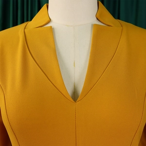 Détail du col en V d'une robe jaune moutarde avec taille haute plissée sur un mannequin