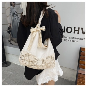 Close-up of ivory canvas tote bag featuring floral lace拼接 and a large bow detail