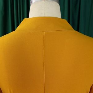 Gros plan détaillé de la texture du tissu jaune moutarde sur le col et l'épaule de la robe