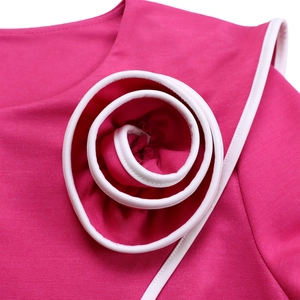 Detail of rose pink dress featuring a large 3D spiral flower with white edge piping