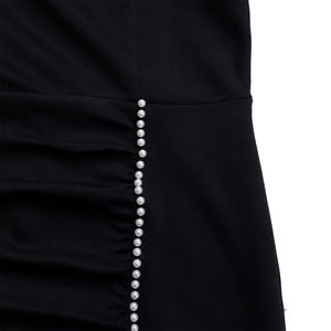 Detail van elegante witte parels en geplooide naden op zwarte kokerjurk stof