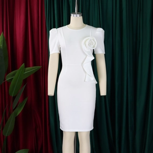 Detail of elegant white dress featuring a 3D floral accent and ruffled layers