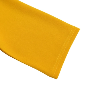 Détail de manche de robe plissée jaune montrant le tissu texturé et l'ourlet piqué