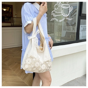 Detailed view of white canvas tote with intricate hollow flower lace and a lace bow accent