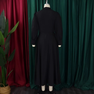 Rear view of a black long-sleeved high-waist maxi dress with a pleated flowing hemline