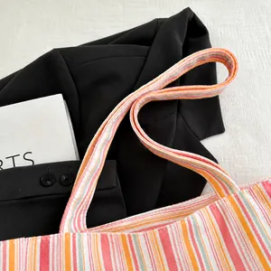 Detail shot of the reinforced handle on a colorful striped canvas tote bag for women