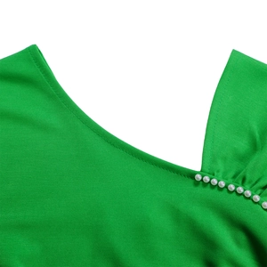 Detailopname van een gifgroene V-hals met witte imitatieparels op de jurk
