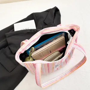 Detail view of colorful striped canvas tote bag showing spacious interior with books