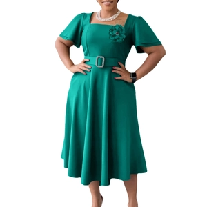 Detail of emerald green dress featuring a floral accent and rhinestone buckle belt