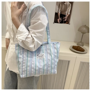 Detail of striped canvas tote bag with a white Fashion label on the shoulder bag