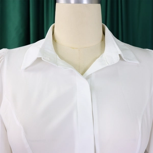 Detail of elegant white long sleeve shirt dress featuring standard collar and pleated cuffs