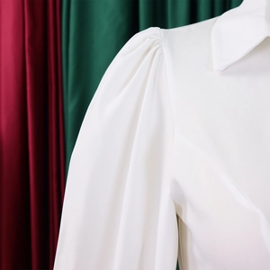 Detailed view of white long-sleeved shirt with puff sleeve pleats and classic pointed collar