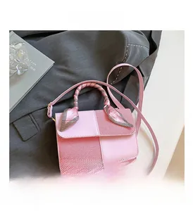 Pink patchwork crossbody bag with silk scarf handle detail on grey blazer background