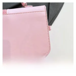 Close-up of pink textured faux leather with precise stitching on a small square bag