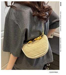 Detail of a cream woven crescent bag with gold metal handle and chain on model