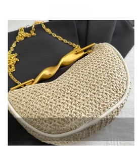 Detail of woven cream handbag featuring a twisted gold metal handle and chain strap