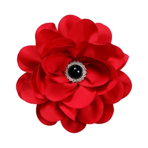 Detail of vibrant red satin flower brooch with a black gemstone and crystal center