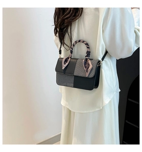 Detail of a chic patchwork shoulder bag with checkered fabric and silk scarf handle