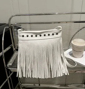Detalle del bolso de cubo en cuero blanco con tachuelas de metal y flecos largos