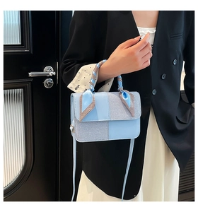 Close-up of light blue patchwork handbag with decorative scarf on handle and shoulder strap