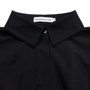 Detail of the black shirt collar featuring Metamorphosis Girl brand label and size S tag