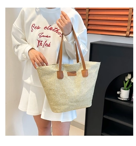 Gros plan détaillé du sac seau tissé beige avec anses en cuir marron et patch mode