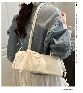 Detalle del bolso de hombro blanco brillante con lazo de encaje y cintas decorativas
