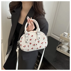 Detail of white mini cherry print handbag with double handles and slim shoulder strap