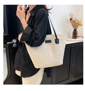 Détail du cabas tissé beige montrant la texture quadrillée et la bandoulière en cuir noir