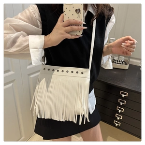 Detalle del bolso de cubo blanco con borlas, tachuelas y flecos largos decorativos