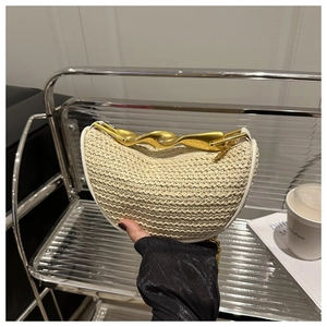 Detail of cream woven half-moon bag featuring a wavy gold metal handle and chain strap