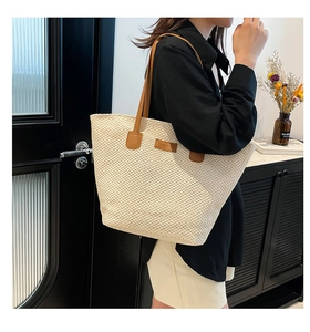 Détail du sac cabas tressé beige montrant la texture raffinée et l'anse en similicuir brun