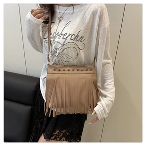 Detalle del bolso de cubo beige con remaches plateados y flecos largos de cuero