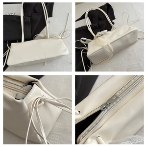 Detalle del bolso de hombro crema con lazo de seda y textura de cuero suave y liso