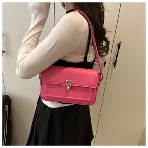 Gros plan du sac porté épaule rose avec texture litchi et fermoir doré semi-circulaire