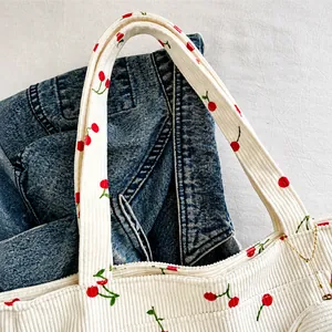 Détail de la poignée en velours côtelé sur le sac cabas crème à motif cerise
