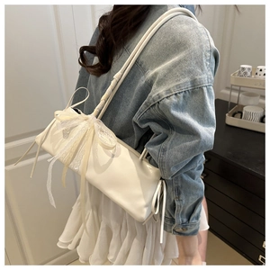 Detalle de un bolso de hombro blanco con un gran lazo de encaje y cintas decorativas
