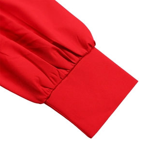 Detailed close-up of vibrant red dress sleeve featuring elegant pleated cuff details