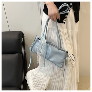 Detalle del bolso de cuero sintético azul claro con colgantes de lazo de encaje y asa anudada