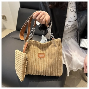 Detail of light brown corduroy tote bag with chain strap and leather logo tag
