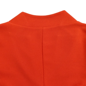 Détail de la robe rouge plissée montrant le col en V et la texture du tissu de qualité