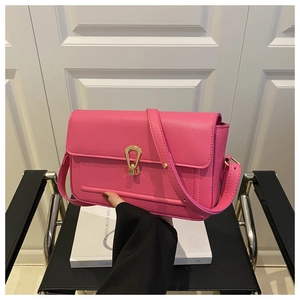Détail d'un sac bandoulière rose en cuir grainé avec boucle en métal doré distinctive