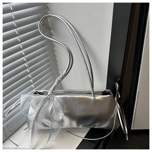 Primer plano del bolso de cuero metalizado plateado con detalle de lazo de encaje blanco