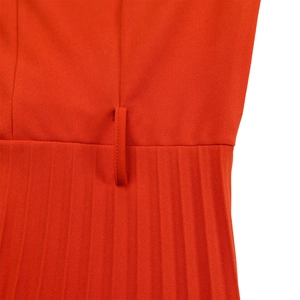 Détails de robe plissée rouge montrant les coutures fines et la boucle de ceinture
