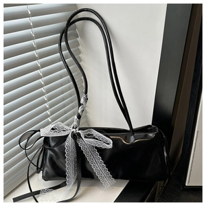 Detalle de bolso de hombro negro brillante con un lazo de encaje blanco en el lateral