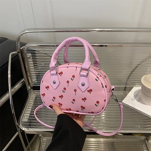 Pink semi-circle handbag with cherry print, featuring dual handles and a long shoulder strap