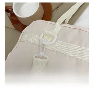 Detail of durable white plastic swivel hook and D-ring on beige nylon shoulder bag