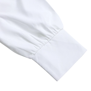 Detail view of the pleated white cuff and sleeve texture of an elegant shirt dress